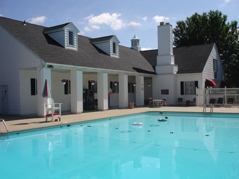 a swimming pool in front of a white house with a large pool